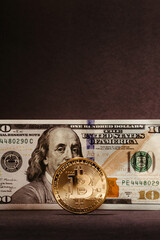 bitcoin coin with 100 dollar paper bill in the background