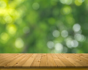 Empty brown plank wooden board mock up display as shelf or desk with blurred bokeh background of green tree in the garden.