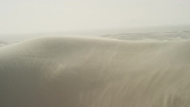 Wide shot of wind skimming over white sand dunes in California