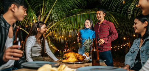 Portrait of Happy Asian friends having dinner party together - Young people sitting at bar table toasting beer glasses dinner outdoor  - People, food, drink lifestyle, new year celebration concept.