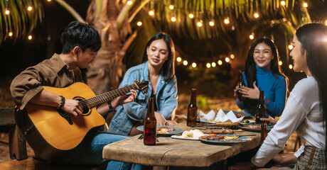 Naklejka premium Portrait of Happy Asian group of friends having fun to music dining and drinking together outdoor - Happy friends group toasting beers - People, food, drink lifestyle, new year celebration concept.