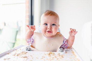 Happy baby in high chair with messy food