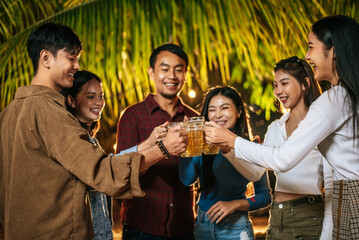 Portrait of Happy Asian friends having dinner party together - Young people toasting beer glasses dinner outdoor  - People, food, drink lifestyle, new year celebration concept.