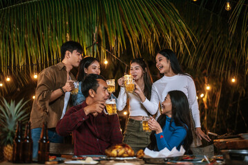Portrait of Happy Asian friends having dinner party together - Young people toasting beer glasses dinner outdoor  - People, food, drink lifestyle, new year celebration concept.