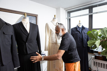grey hair bearded man wearing skirt designing tailored fashion