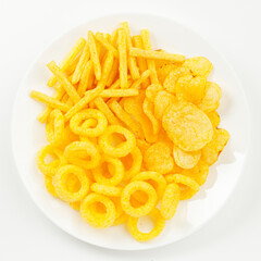 A pile of salty snacks with spices on a white plate, close-up.