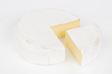 A piece of ripe Camembert cheese on a white plate, for baking.