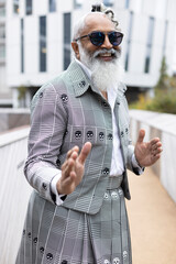 gray hair bearded man wearing skirt suit laughing and gesturing