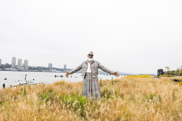 man with gray hair and beard, arms outstretched in waterfront natural area