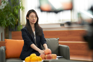 Asian anchorwoman waiting and preparing for interview in studio 