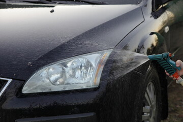 Wet car front washing outdoor with hose Garden gun sprayer in Summer