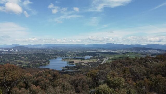 Aerial flyby of Telstra Tower in Canberra, the capital of Australia, showing a panoramic view of Lake Burley Griffin and surrounding landmarks and countryside