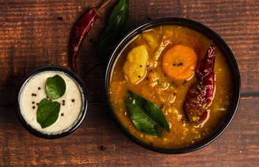 Shot of Sambar and coconut chutney arranged on black bowls on a wooden background. Sambar and chutney are popular in South Indian and Sri Lanka cuisines.