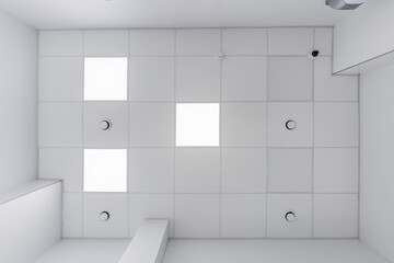 cassette stretched or suspended ceiling with square halogen spots lamps and drywall construction with fire alarm and ventilation in empty room in house or office. Looking up view