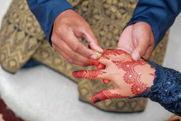 Malay wedding bride put a ring on her bride.