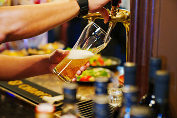 Fototapeta na wymiar men's hands pour beer into a beer tap glass.