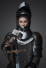 Shot of knight woman with sword dressed in chainmail and helmet.