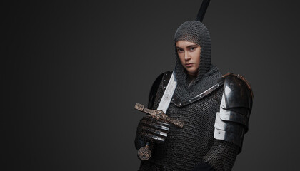 Studio shot of female knight holding sword and looking at camera.