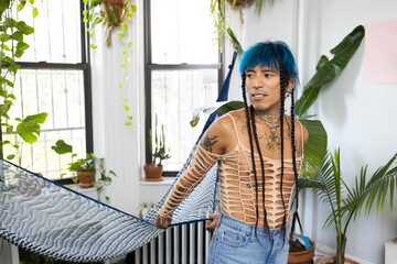 indigenous non-binary artist with blue hair and braids at home