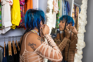 indigenous non-binary artist with blue hair looking in mirror