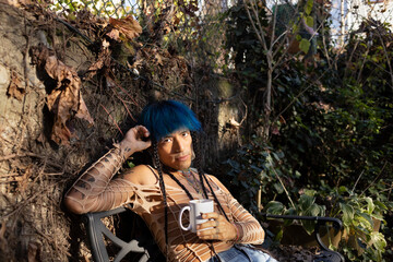 indigenous non-binary artist drinking tea in urban garden in autumn