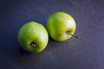 Fresh juicy ripe green apples on a dark gray background.