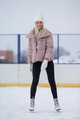 Young Caucasian Girl in Winter With Ice Skates Posing Over a Snowy Winter Landscape Outdoor.