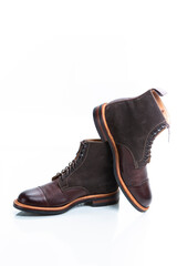 Pair of Premium Dark Brown Grain Brogue Derby Boots Made of Calf Leather with Rubber Sole Placed Over One Another Over White