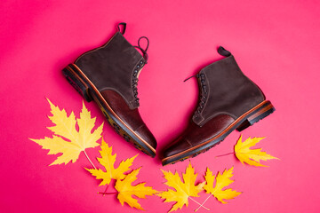 Flatlay View of Premium Dark Brown Grain Brogue Derby Boots Made of Calf Leather with Rubber Sole Placed With Yellow Maple Leaves Over Pink.