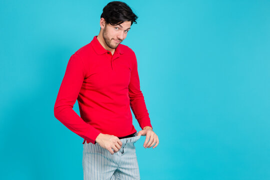 Funny Ideas. One Smiling Caucasian Handsome Brunet Man in Striped Underware Pulling Pants While Looking Aside Against Seamless Blue
