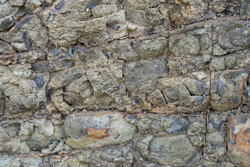 The gray volcanic rock layer formed by the deposition of volcanic magma is a natural beauty.  The stone has weathered over time.  The quarrying industry reveals beautiful strata.  abstract background.