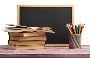 Stack of books with chalk blackboard and colored pencils on the wooden table.