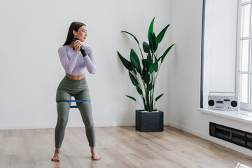 Pretty brunette caucasian fit girl in sportswear with artificial hand makes exercise at home using...