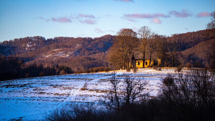panorama of krywe village in polish bieszczady mountains by the san river; old destroyed orthodox church on the hill in snowy winter weather