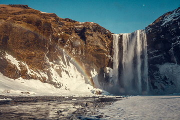 Fototapeta na wymiar Skogafoss waterfall with rainbow landscape photo. Beautiful nature scenery photography with clear sky on background. Idyllic scene. High quality picture for wallpaper, travel blog, magazine, article