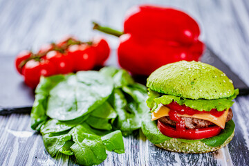 Side view of green homemade burger with marble beef with veggies on wooden table. Selective focus 