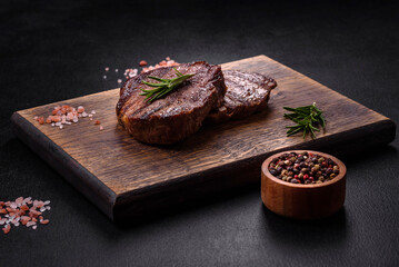 Delicious fresh juicy beef steak with spices and herbs on a dark concrete background