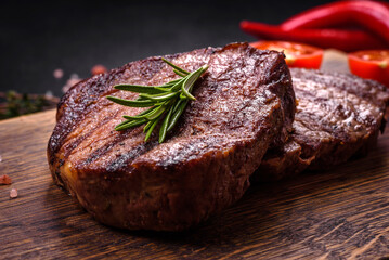Delicious fresh juicy beef steak with spices and herbs on a dark concrete background