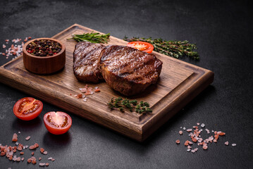 Delicious fresh juicy beef steak with spices and herbs on a dark concrete background