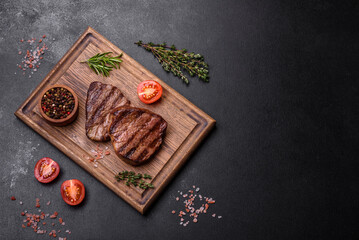 Delicious fresh juicy beef steak with spices and herbs on a dark concrete background