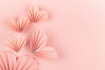 Soft light pastel pink paper hearts of asian fribbed fans soar on pink background, top view. Festive Valentines day, wedding, love backdrop for card, text, design, greeting, invitation, advertising.