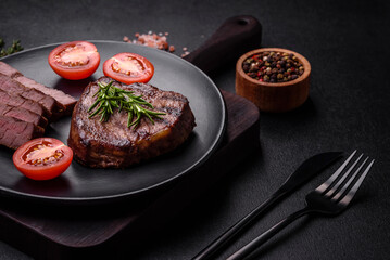 Delicious fresh juicy beef steak with spices and herbs on a dark concrete background
