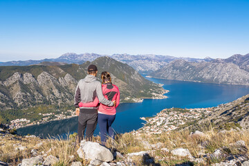 Loving couple hugging with panoramic view of Kotor bay in sunny summer, Adriatic Mediterranean Sea,...