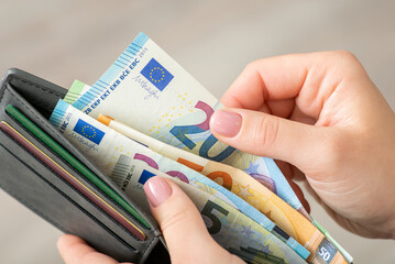 Close up of female hands holding grey wallet with 20 and 50 euro banknotes. Purchases, business, finances concept - obrazy, fototapety, plakaty