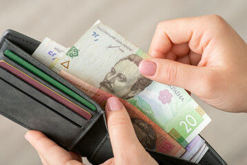 Small money in the wallet, paying for goods concept. Woman dealing with finances, using ukrainian hryvnias while shopping