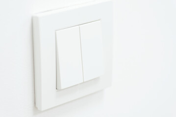Plastic mechanical switch of white color installed on white wall. Turn on and off the light in dark...