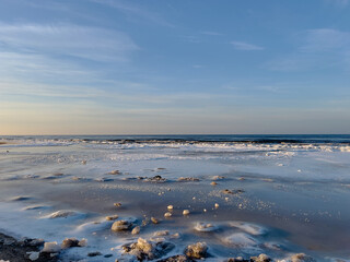 Winter landscape with sea covered with ice and blue clear sky above, selective focus