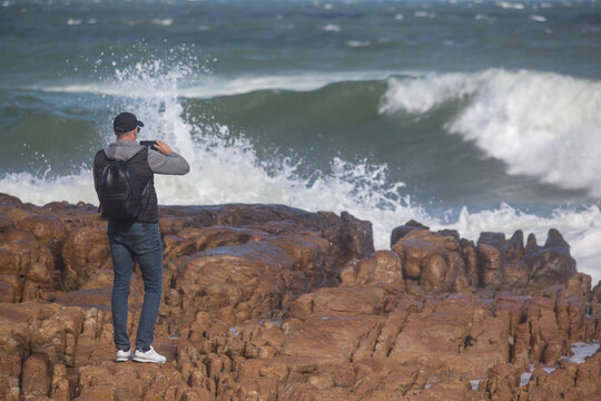 a man takes pictures of the Atlantic Ocean on his smartphone. South Africa