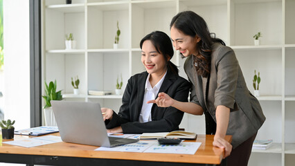 Professional Asian female boss is training and coaching her new assistant, working together