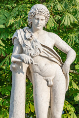 Obraz premium Old park statue of Renaissance Era Roman man hunter in lion skin with hunting tube in city park, Potsdam, Germany